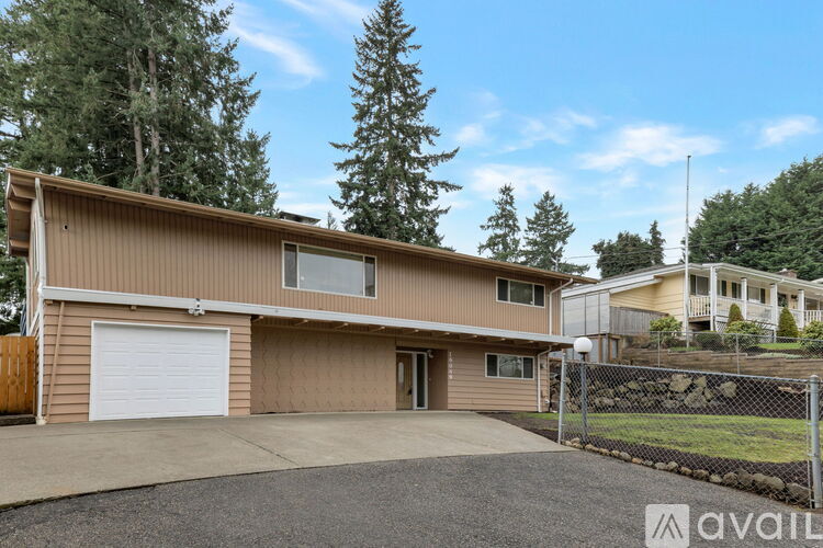 A house with a brown exterior and a white garage door is available for sale.