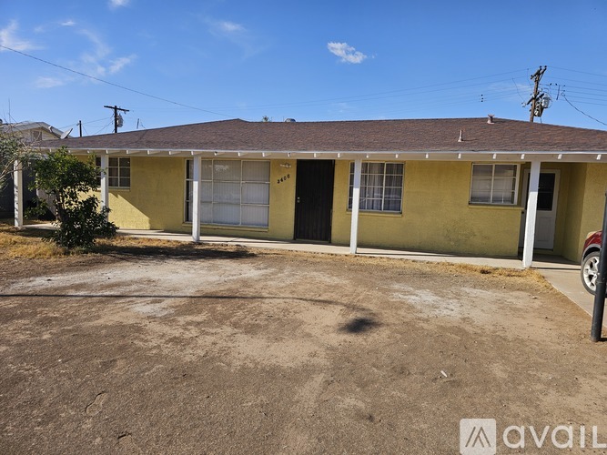 A yellow house with a brown roof and a white fence.
