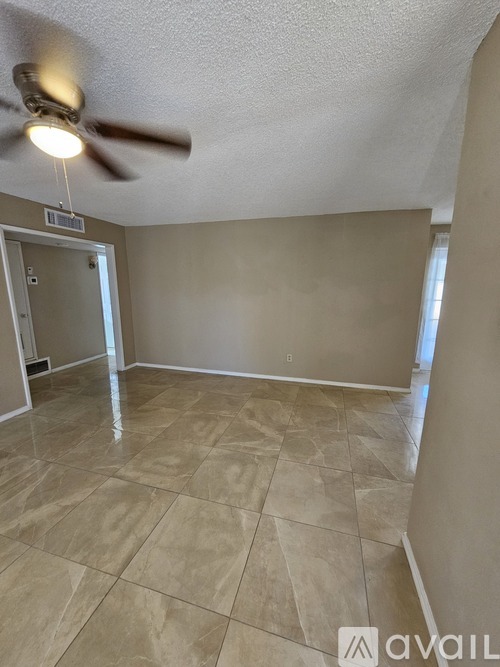 A room with a ceiling fan and tile flooring.
