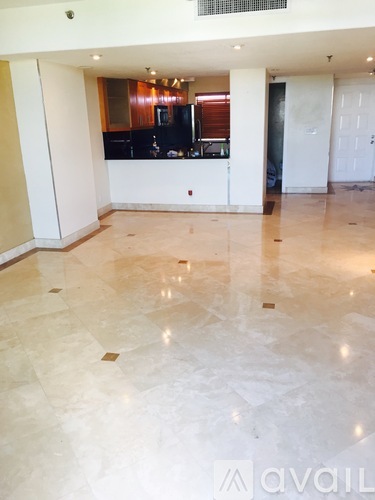 A spacious room with a marble floor and a bar area in the background.