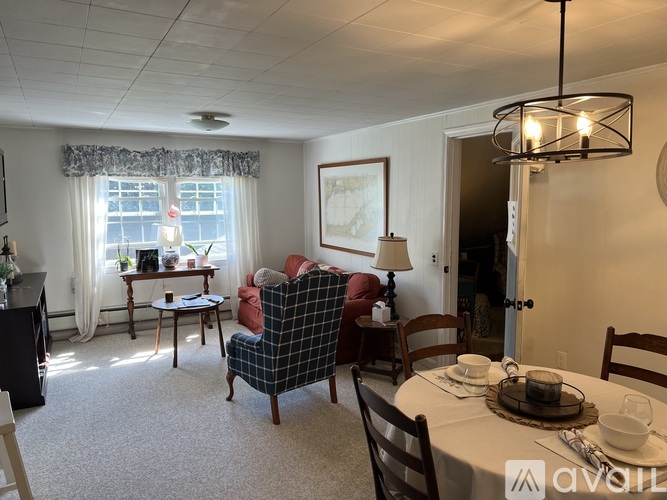 A dining room with a table set for two and a couch.