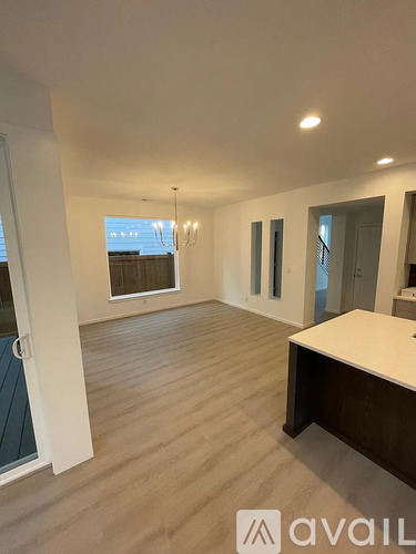 A spacious room with wooden flooring and a large window.