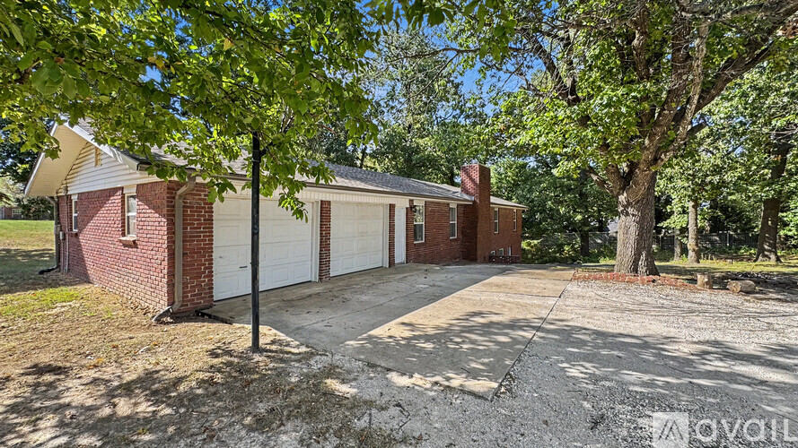 A house with a white garage door is surrounded by trees.