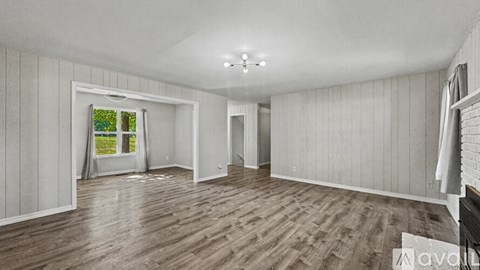 A spacious room with wooden flooring and white walls.