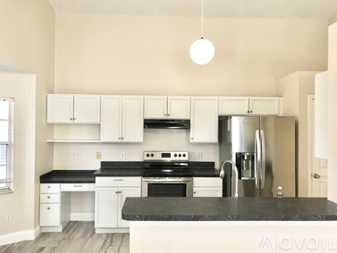 A kitchen with white cabinets and black countertops.
