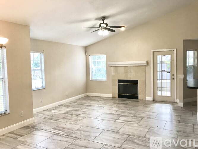 A spacious room with a fireplace and a ceiling fan.