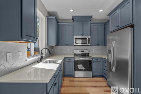 A kitchen with a white counter top and a stainless steel refrigerator.