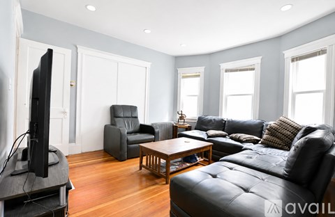 A living room with a black leather couch and a television.
