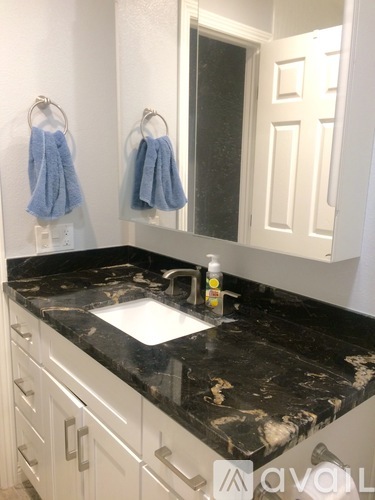 A bathroom with a black granite counter top and white cabinets.