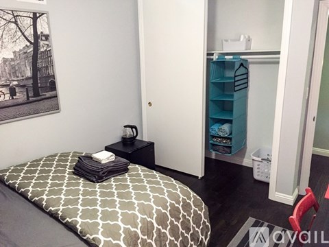 A bedroom with a bed, a chair, and a cabinet.