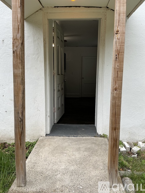 A white doorway with a concrete floor and wooden posts.