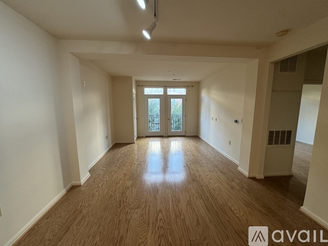 A spacious room with wooden flooring and a large window.