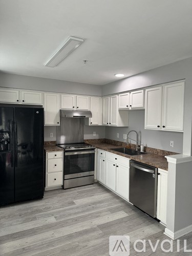 A kitchen with white cabinets and a black refrigerator.
