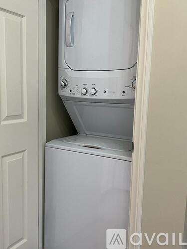 A white dishwasher and dryer are stacked in a small space.