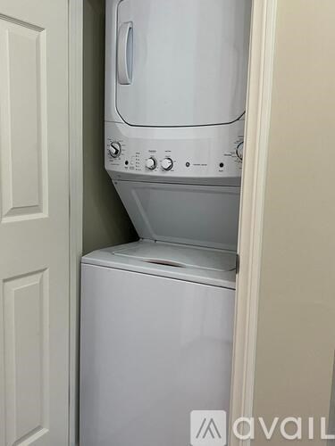 A white dishwasher and dryer are stacked in a small space.