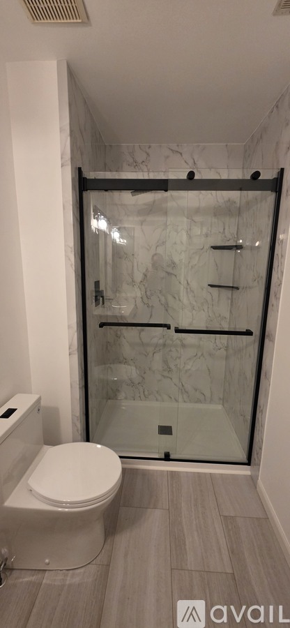 A bathroom with a toilet, a walk-in shower, and a towel bar.