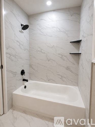 A white bathroom with a marble wall and a white bathtub.