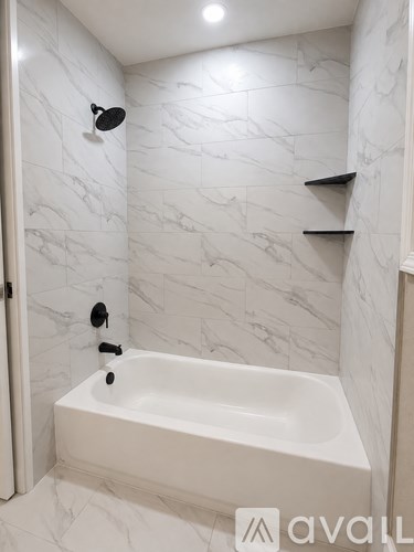 A white bathroom with a marble wall and a white bathtub.