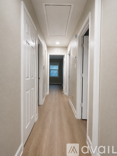 A long hallway with white walls and wood flooring.