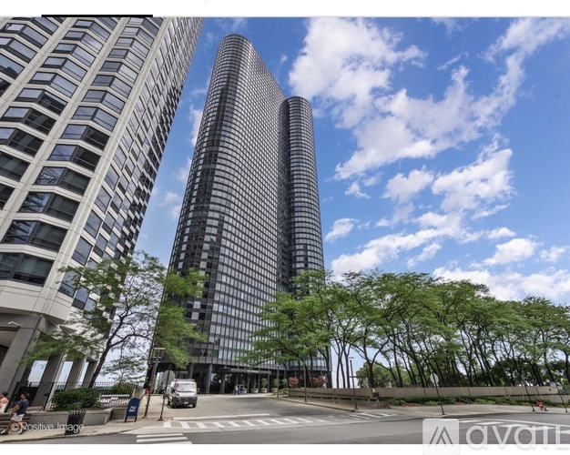 A tall building with a curved glass facade stands next to a shorter building with a grid-like facade.