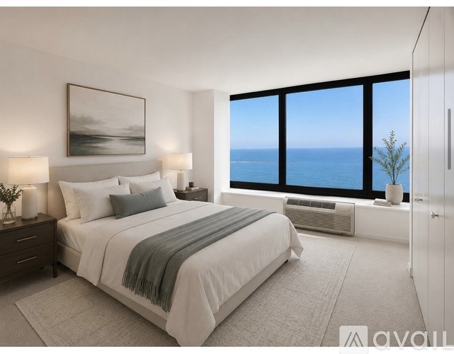 A bedroom with a large bed and a view of the ocean through the window.