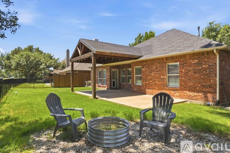 A house with a red brick exterior and a covered patio area with two chairs and a table.
