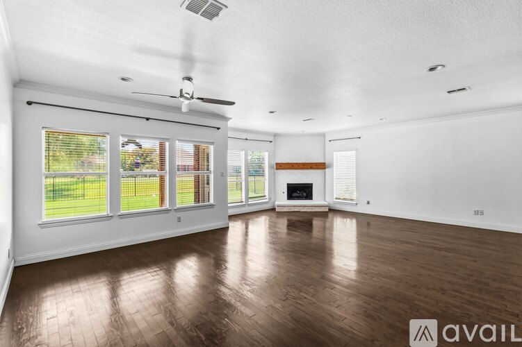 A spacious room with a fireplace and a fan on the ceiling.