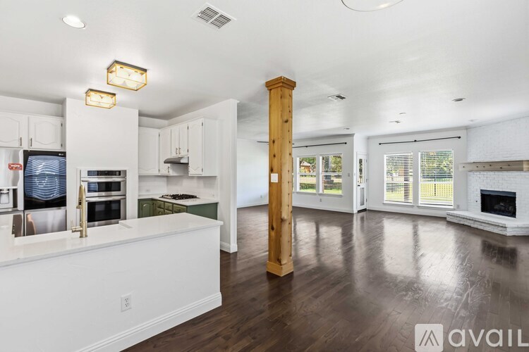 A modern kitchen with white cabinets and a wooden column in the middle.