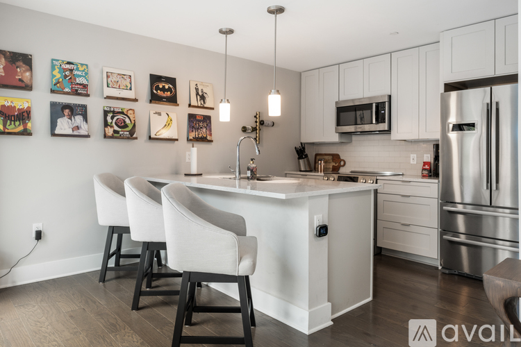 A kitchen with white cabinets and a white island with chairs around it.