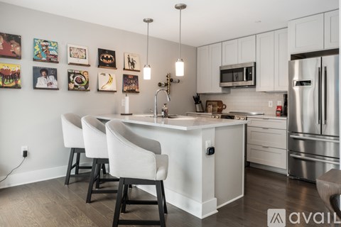 A kitchen with white cabinets and a white island with chairs around it.