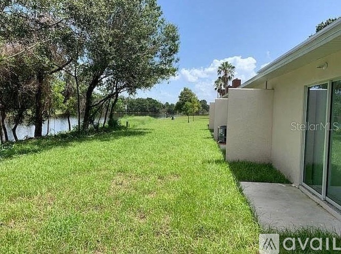 A house with a yard and a body of water in the background.