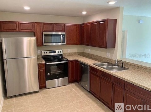 A kitchen with brown cabinets and a stainless steel refrigerator.