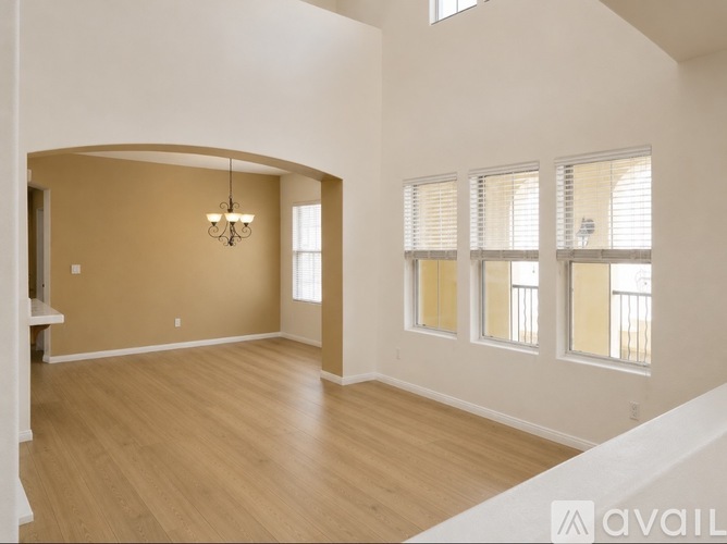 A spacious room with wooden floors and a chandelier hanging from the ceiling.