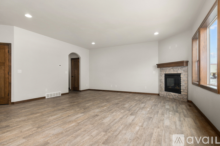 A spacious room with a fireplace and wooden flooring.