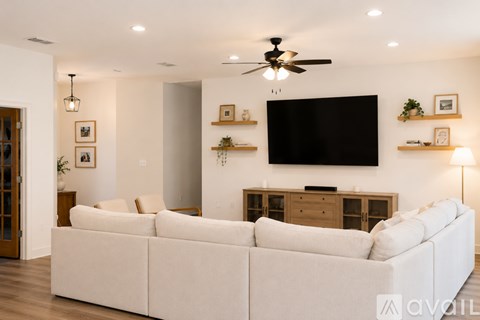 A living room with a white couch and a flat screen TV mounted on the wall.
