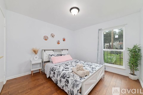 A bedroom with a large bed and a window overlooking a grassy area.