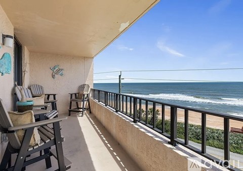 A balcony with chairs and a table overlooking the ocean.