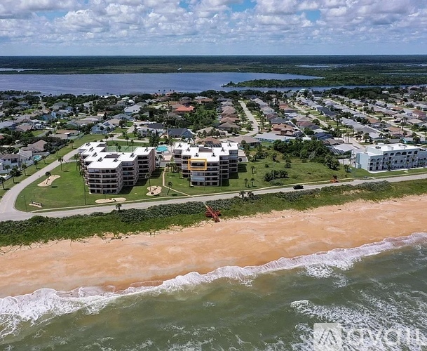 A beachfront community with apartment buildings and a sandy beach.