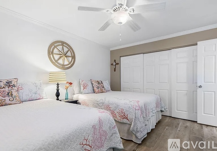 A bedroom with two beds and a ceiling fan.