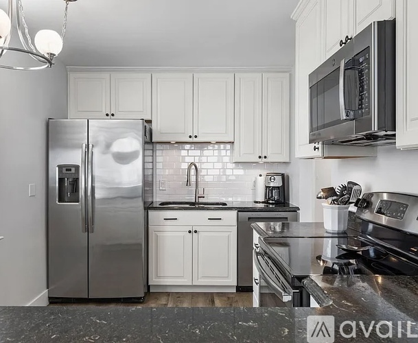A kitchen with white cabinets and a stainless steel refrigerator.