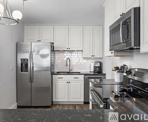 A kitchen with white cabinets and a stainless steel refrigerator.