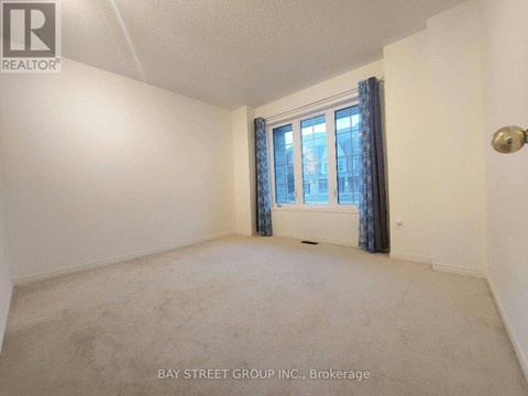 A room with a window and curtains, with a carpet on the floor.