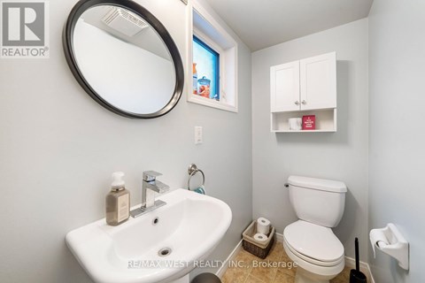 A bathroom with a sink, toilet, and a mirror.