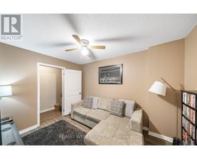 A living room with a couch, a ceiling fan, and a picture on the wall.