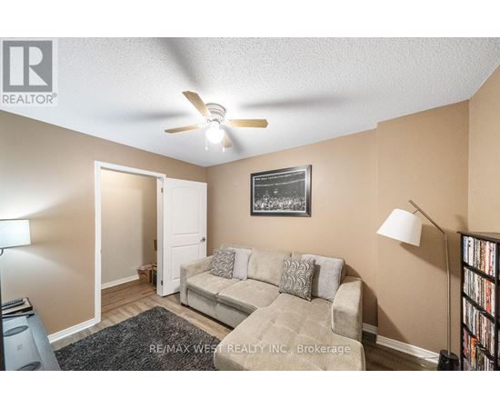 A living room with a couch, a ceiling fan, and a picture on the wall.