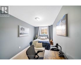 A bedroom with a bed, chair, and two pictures on the wall.