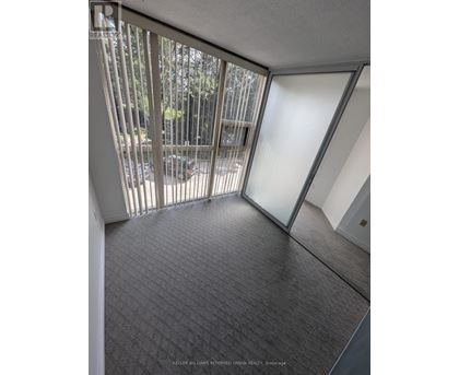 A room with a carpeted floor and a glass door leading to a balcony.
