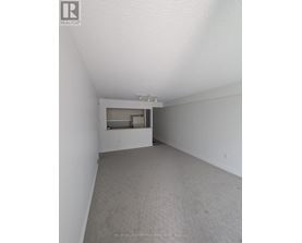 A spacious room with a carpeted floor and a window.
