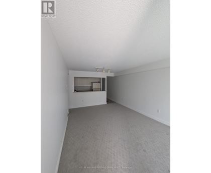 A spacious room with a carpeted floor and a window.
