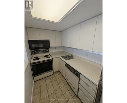 A kitchen with white cabinets and a black microwave.
